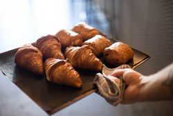 Chef removing tray of croissant from oven