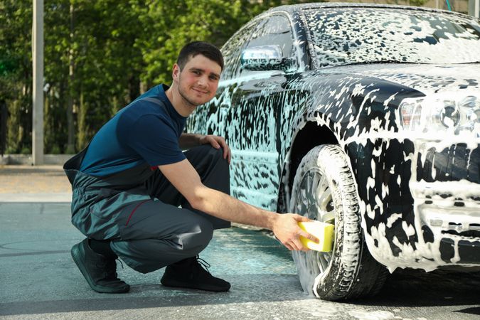 Man wipes the car with a sponge. Car wash. Clear car concept