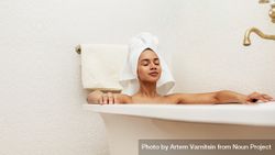 Woman relaxing in bath with towel on head 4mkJB0