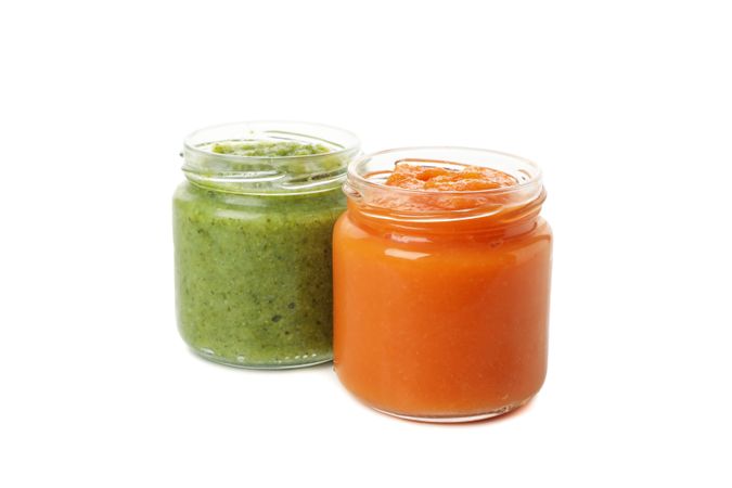 Glass jars with healthy baby food isolated on plain background