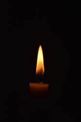Side view of candle lit in the dark with copy space