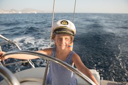 Smiling girl holding steering wheel on yacht on water