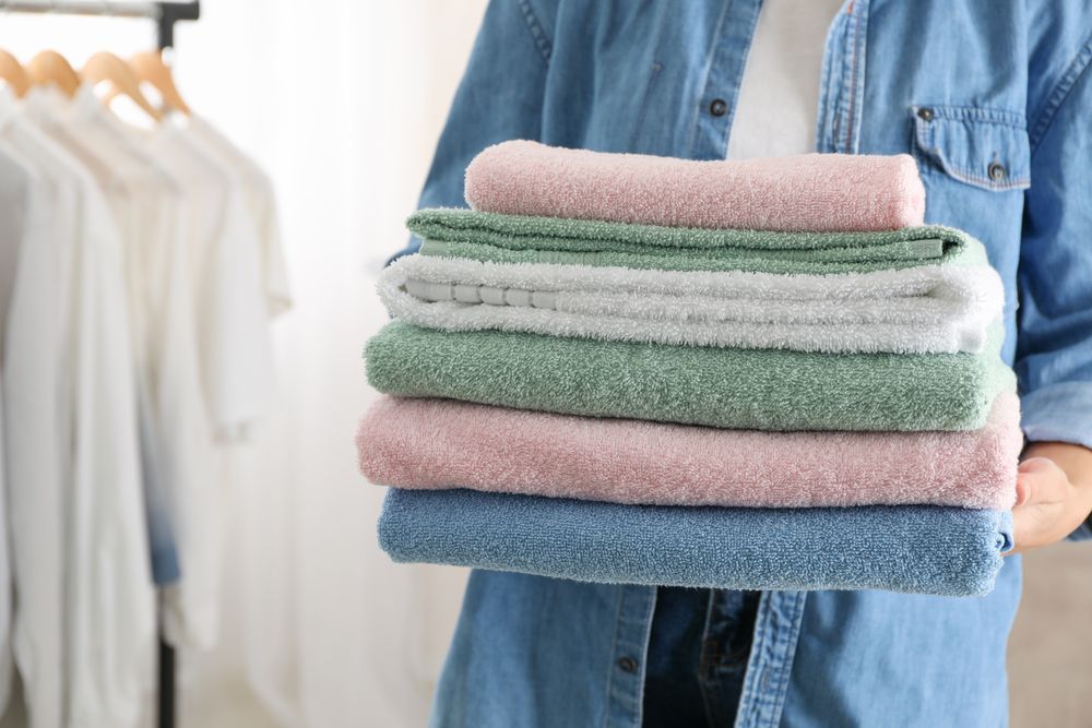 Young woman hold clean towels, close up and space for text