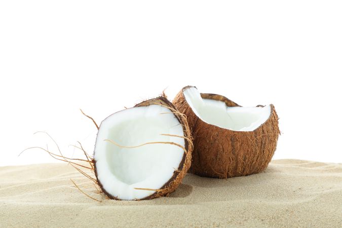 Coconuts on clear sea sand isolated on plain background. Summer vacation
