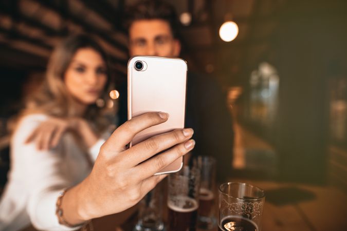 Close up of woman holding smart phone while taking selfie with male