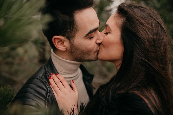 Happy couple hugging among pine forest
