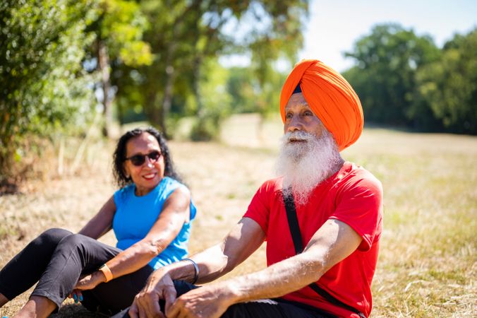 Mature Sikh couple doing sit ups in park