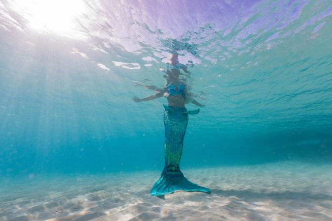 Blond fairytale female mermaid swimming underwater