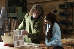 Woman choosing sample with carpenter in workshop