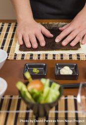 Hands of female chef ready to prepare sushi rolls, with fresh ingredients in the foreground, vertical 0PxZ70