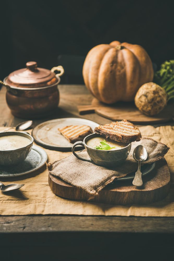 Celery soup in cups with toast, spoon, cloth napkin, on wooden board