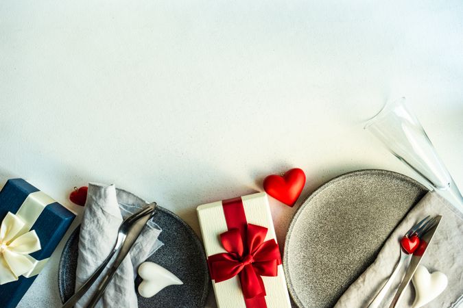 Top view of two grey plates with champagne flutes and presents