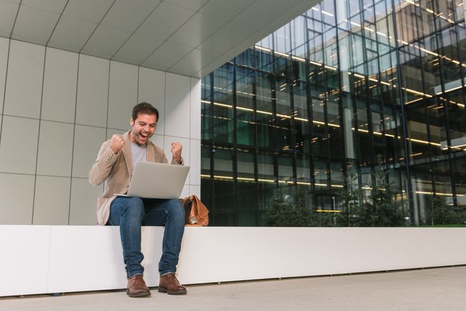 Cheerful businessman using laptop on street