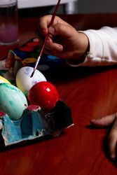 Hand of child painting Easter eggs