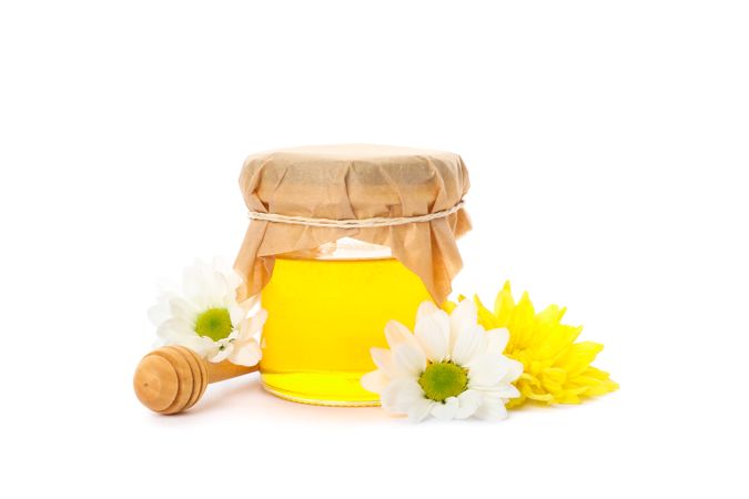 Glass jar with honey, chrysanthemum, chamomile and dipper isolated on blank background