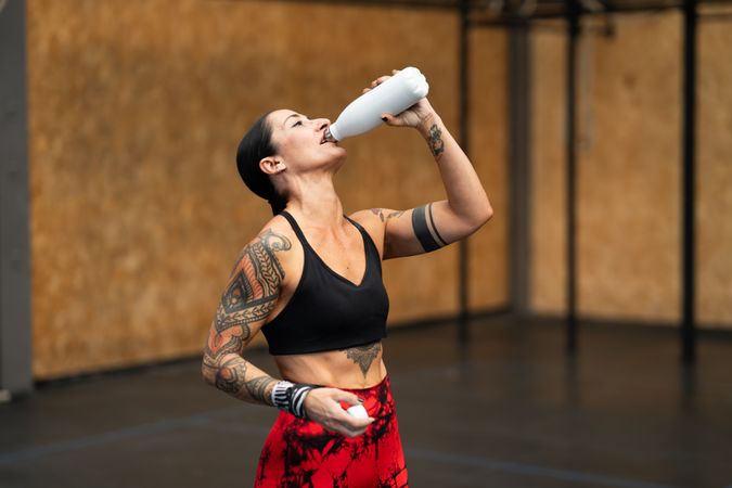 Tattooed fit woman drinking water