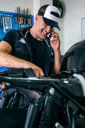 Mechanic talking phone while fixing motorbike