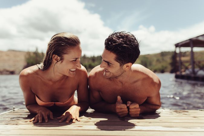 Young man and woman on wooden jetty after a swim in lake