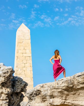 Woman in dress standing near stone monument