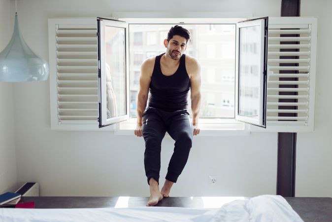 Young happy man sitting on window