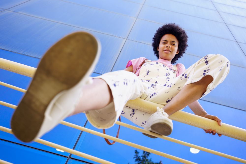 Low angle shot of woman sitting on handrails in front of  reflective office building