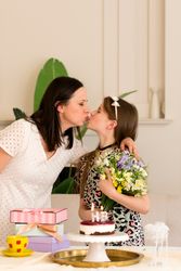 Mother and daughter sharing kiss during birthday celebration