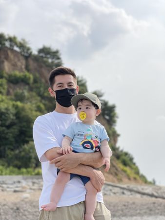 Man with facemask holding a baby