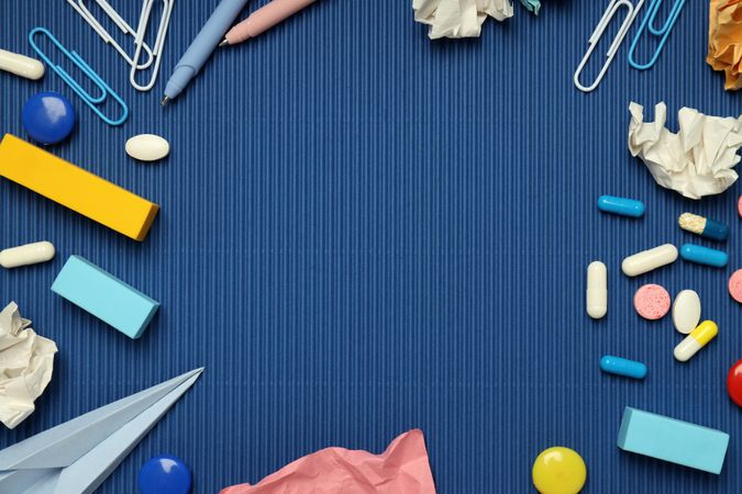 Flat lay of stationary and pills on a blue background