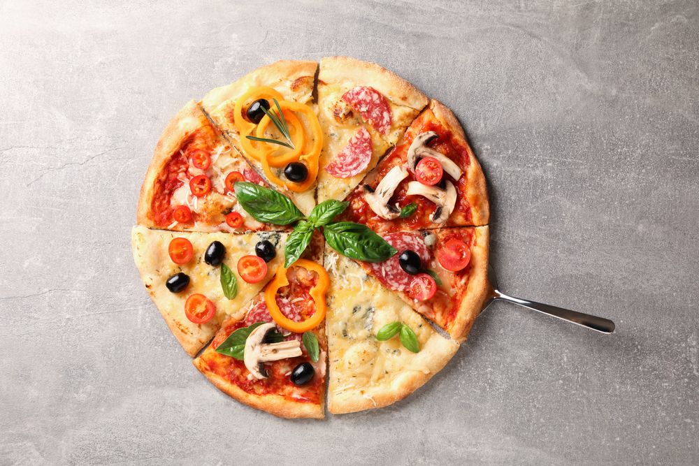 Delicious pizza with different pieces on grey background, space for text
