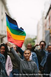 Female holding the gay rainbow flag at a pride event in city 49RXEb