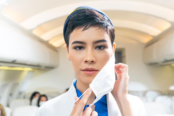 Flight attendant taking off facemask in airplane
