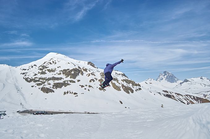Unrecognizable snowboarder jumping on slope
