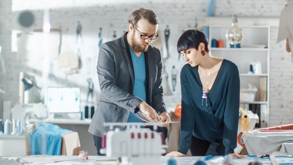 Female and Male fashion, designer,  Choosing Sketches for Their New Clothing Collection. Studio is Sunny.