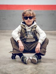 Boy in trendy outfit sitting on skateboard