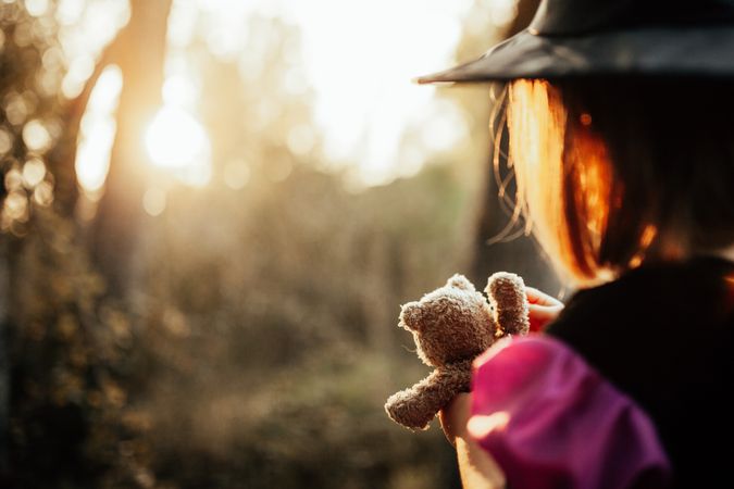 Rear shot of girl with teddy bear in witch costume