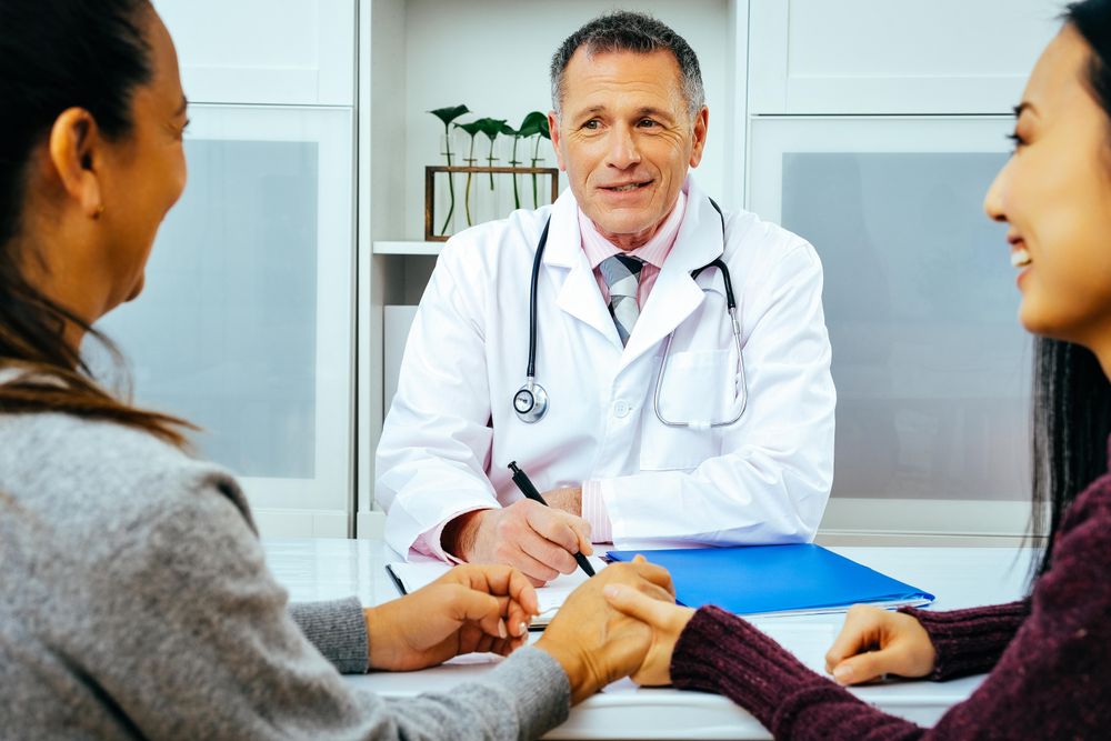 Funny doctor sharing news with two patients in medical office