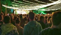Young man listening concert on a summer night music festival in nature