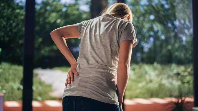Human Going Through Severe Back Pain. Close Up of a Female Experiencing Discomfort in a Result of Spine Trauma or Arthritis.