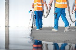 Group of workers pouring concrete floor
