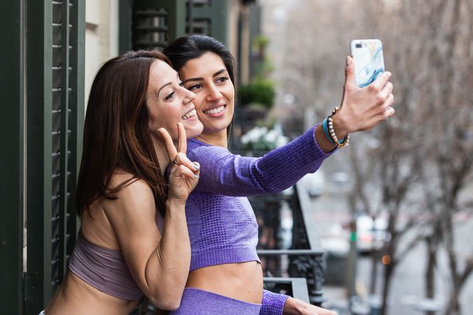 Happy friends taking selfie on balcony