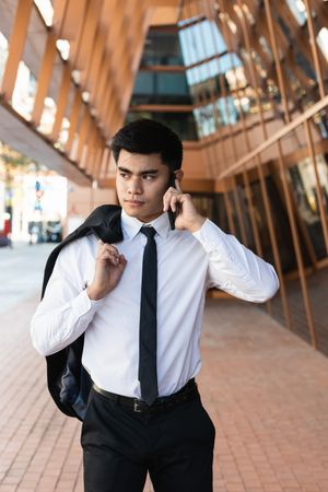 Smiling businessman speaking on smartphone in downtown