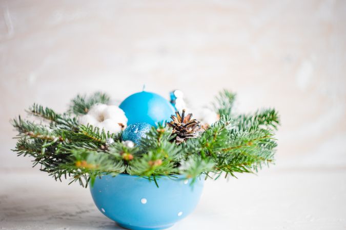 Side view of Christmas wreath with blue baubles and pines on table