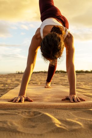 Determined yogi performs downward dog on beach at golden hour: Strength meets serenity