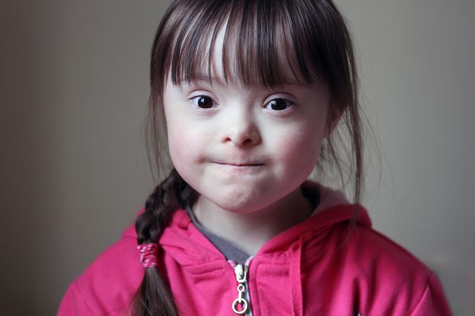 Portrait of a young girl with Down syndrome making a baffled face