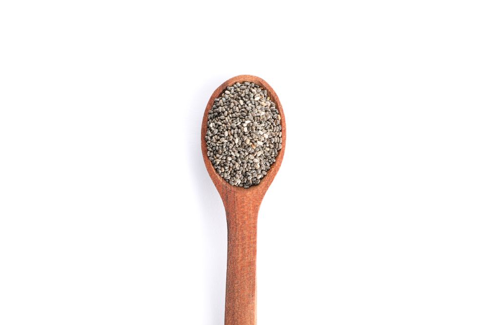 Chia seeds and wooden spoon isolated on studio background