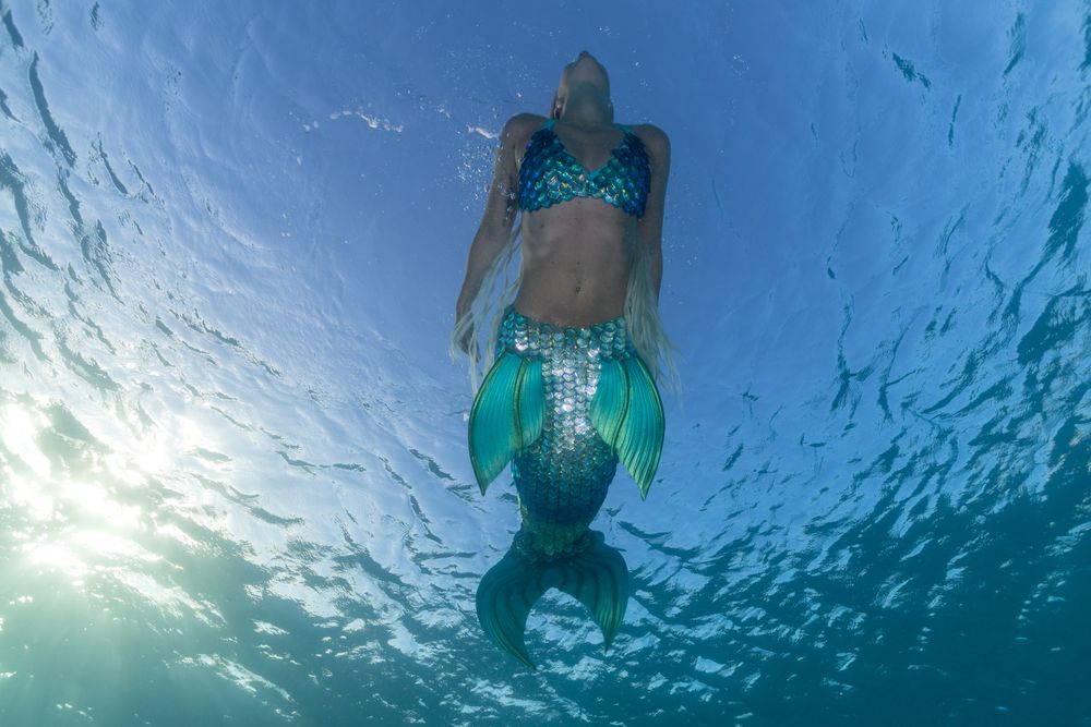 Redhead fairytale female mermaid swimming underwater
