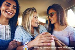 Group of happy female friends chatting with each other while riding in back of vehicle 0g12W4