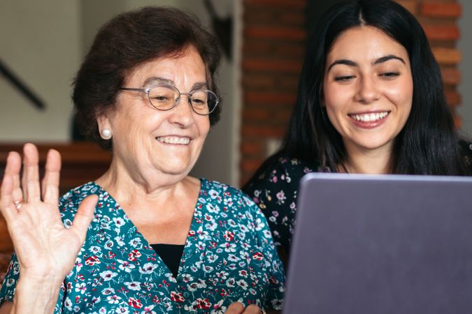 Grandmother and granddaughter making video call with laptop at home