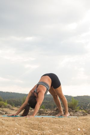 Woman practicing yoga outdoors near water