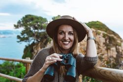 Woman with binocular on coastal walkway